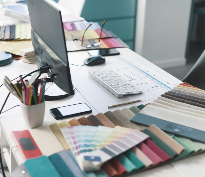 Interior designer work desktop with computer, fabric swatches and house project
