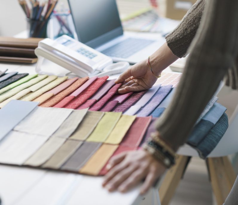 Professional decorator working in her studio, she is choosing fabric swatches for her project